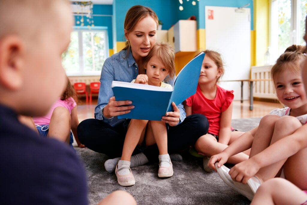 Teacher reading a picture book to children